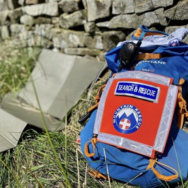 sar store Mountain Rescue marker panel on a rucksack in grass along a dry stone wall